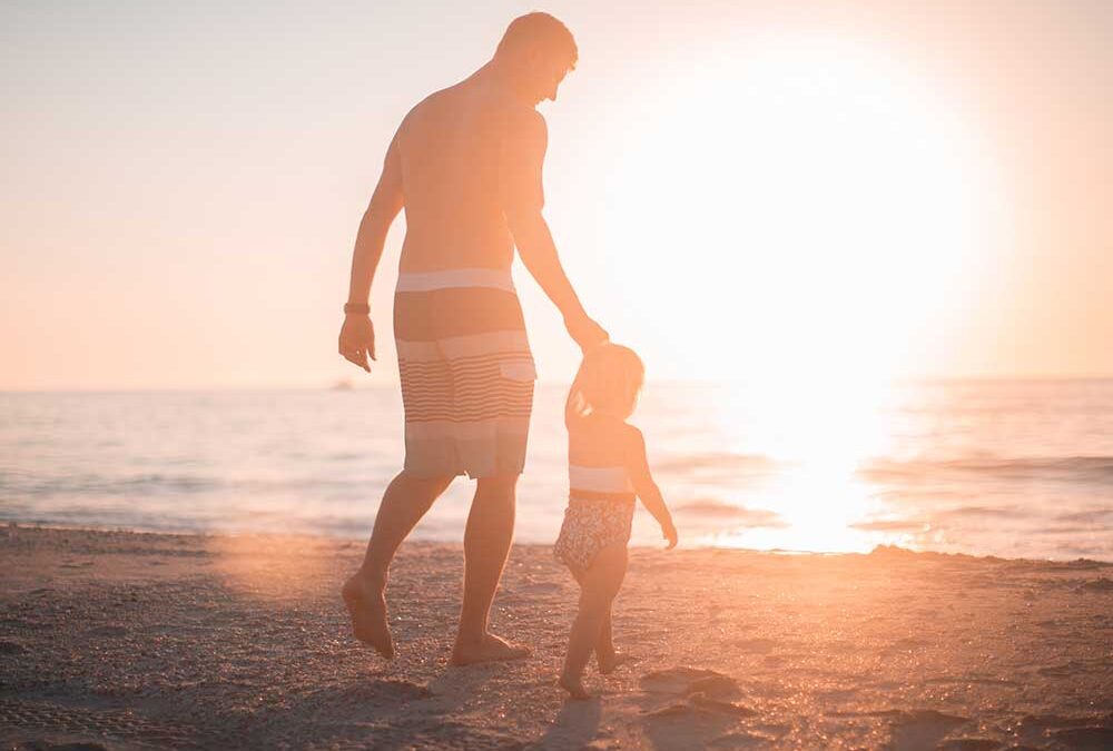 Father and daughter at beach during sunset