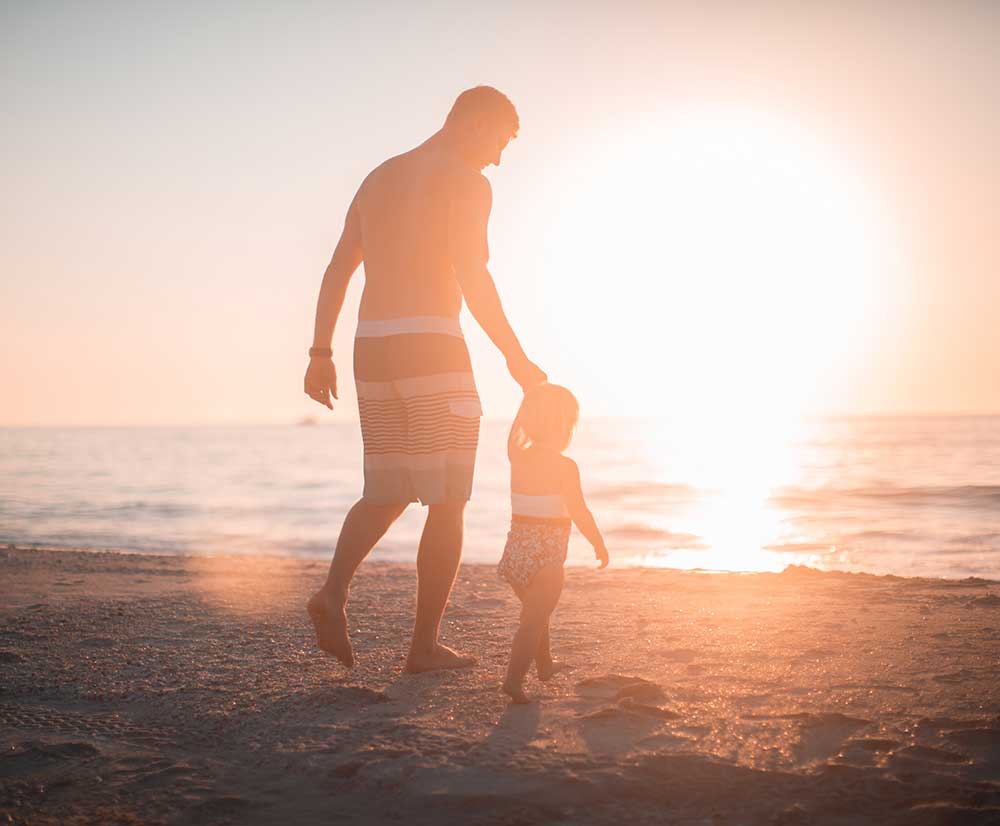 Father and daughter at beach during sunset