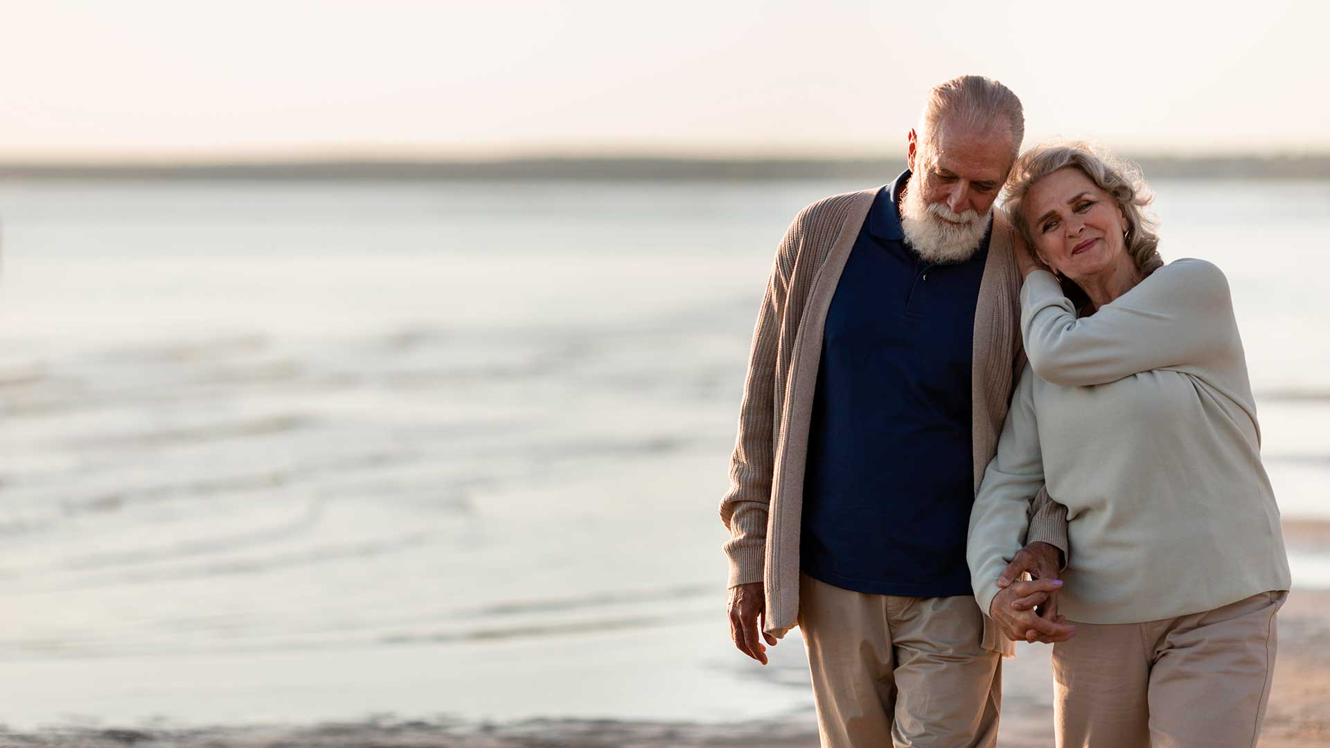 Agent explaining medicare insurance plans Senior couple walking beach