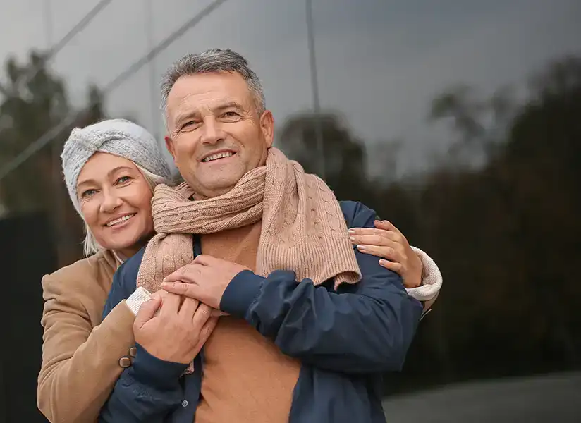 Retired couple hugging by building